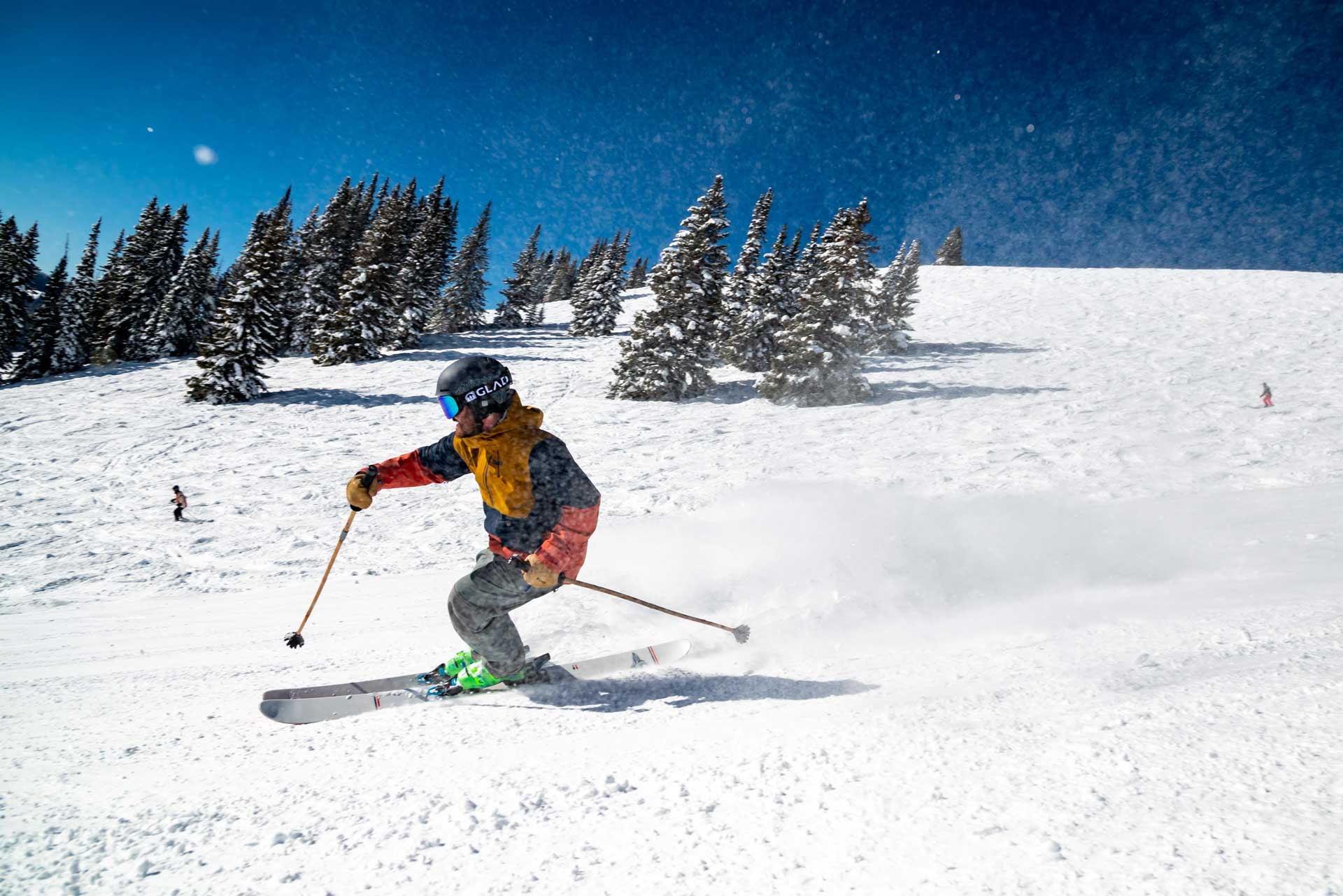 A backcountry skier carving down a snow-covered ridge in the Manang Valley, Nepal.
